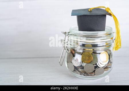 Risparmiare denaro monete in vaso d'erba con banca piggy e tappo di graduazione, business finance Education Concept. Foto Stock