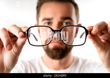 Giovane uomo che tiene gli occhiali nelle mani Foto Stock