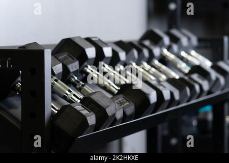 Dumbbell casa blurry parete palestra set di stoccaggio strongman attrezzature, da studio di attrezzature in allenamento e muscolare forte, peso duro. Sollevamento pesi , Foto Stock