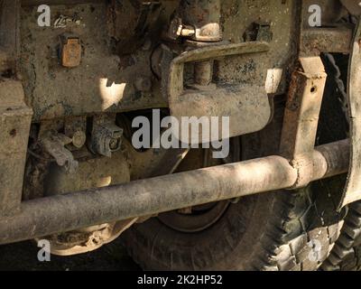 Vista dettagliata del vecchio arrugginito e sporco carrello indietro, pneumatico di grandi dimensioni e meccanismo di traino visibile. Foto Stock