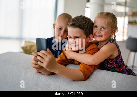 Concetto di smartphone per bambini con tecnologia infantile. Bambini piccoli felici che giocano sul telefono cellulare Foto Stock