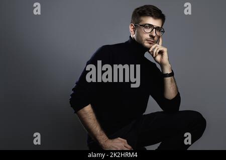 Giovane uomo intelligente che indossa dolcevita e occhiali Foto Stock