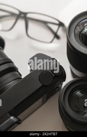 Ambiente di lavoro con attrezzature moderne per la fotografia. Fotocamera Mirrorles e obiettivi a focale fissa. Foto Stock