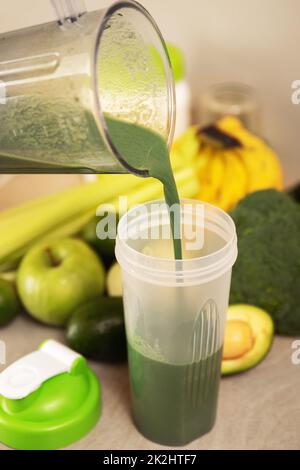 Versare un cocktail vegetariano verde nello shaker Foto Stock