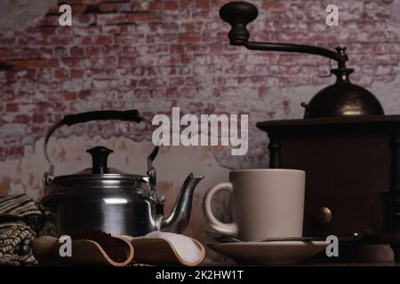 tazza da caffè con caraffa per il latte, macinacaffè e cucchiai di legno con caffè macinato allo zucchero Foto Stock