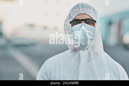 Siamo noi contro il virus. Colpo di un giovane uomo vestito con il suo equipaggiamento protettivo prima del processo di decontaminazione. Foto Stock