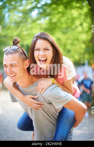 Amore giovane. Un giovane uomo alla moda che dà alla sua ragazza un giro di piggyback. Foto Stock