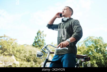 C'è potere nella perseveranza. Scatto di un giovane uomo d'affari usando uno smartphone mentre cavalca la sua bicicletta in città. Foto Stock