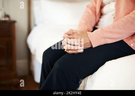 Cosa sto aspettando. Scatto corto di una donna anziana seduta sul bordo di un letto in una casa di cura. Foto Stock