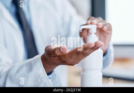 Uccidendo i batteri sul normale. Primo piano di un medico irriconoscibile che utilizza l'igienizzatore per le mani in un ospedale. Foto Stock