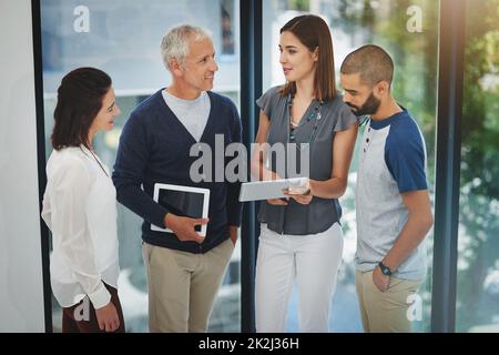 Discussioni informali. Scatto ritagliato di un gruppo di colleghi che hanno una conversazione su un tablet nel loro ufficio. Foto Stock