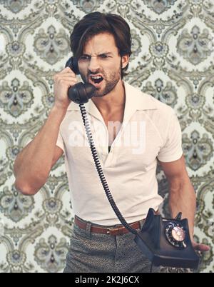 Fatti subito. Un bell'uomo in retrò 70s abbigliamento gridare a qualcuno al telefono. Foto Stock