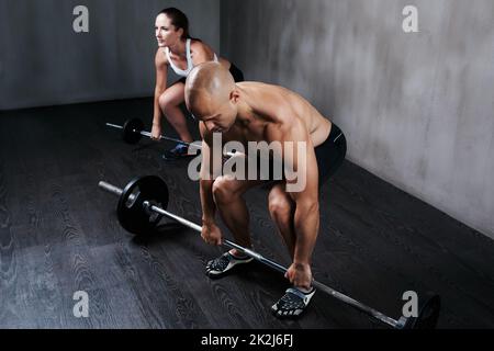 Formazione per diventare in forma di combattimento. Shot di due persone che sollevano campane durante un allenamento in palestra. Foto Stock