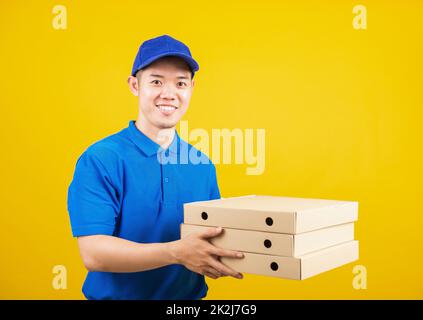 servizio di consegna uomo in piedi lui sorriso indossando t-shirt blu e cappuccio uniforme tenere dare cibo ordine pizza scatole di cartone Foto Stock