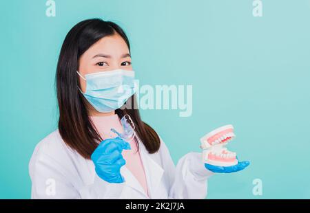 dentista donna che tiene fermi ortodontici in silicone e dentiera modello Foto Stock