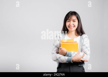 Donna giovane sorridente tenendo e abbracciare abbracciare il libro preferito per l'amante Foto Stock