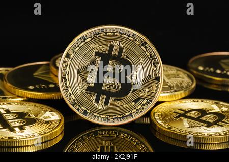 Monete d'oro con simbolo di bitcoin su fondo nero Foto Stock