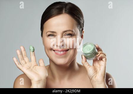 Bella donna di mezza età con maschera di fango verde Foto Stock