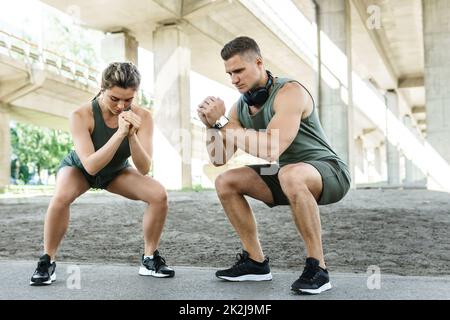 Coppia atletica che fa squat durante l'allenamento di strada Foto Stock
