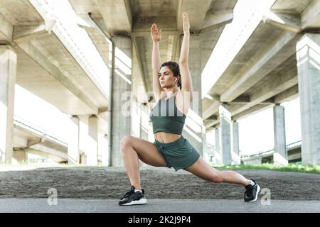 Donna atletica che fa affondi durante il suo allenamento di strada Foto Stock