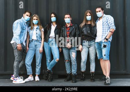 Gruppo di amici che indossano maschere di prevenzione durante la riunione all'aperto. Foto Stock