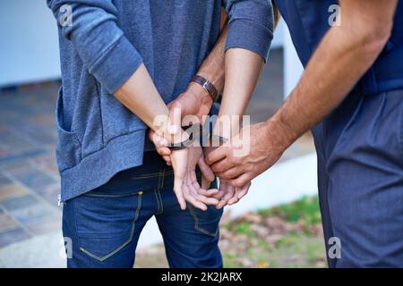 Coccolando un criminale. Il colpo corto di un poliziotto le mani che mettono i polsini su un sospetto. Foto Stock
