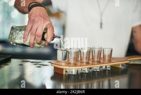 Inizia questa festa. Scatto ritagliato di un barista inidentificabile versando colpi dietro la barra. Foto Stock