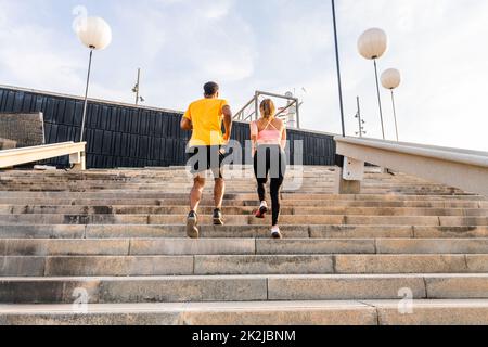 Allenamento sportivo interrazziale di coppia all'aperto - coppia multirazziale indossando abbigliamento sportivo e facendo allenamento funzionale all'aperto per tendere i muscoli del corpo, Foto Stock