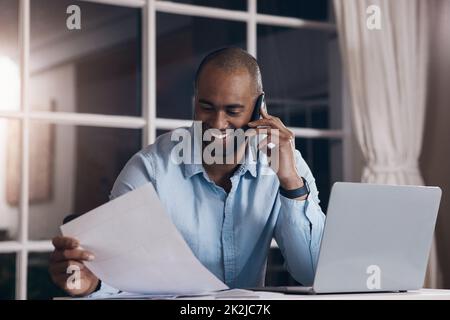 ID amore per gestire alcune idee da voi. Scatto di un giovane uomo d'affari che legge i documenti mentre fa una telefonata usando il suo smartphone. Foto Stock