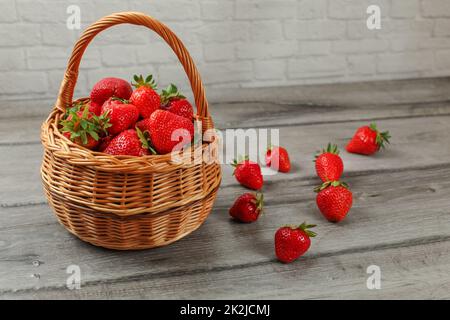 Cesto di Fragole, alcuni di loro versato sul legno grigio desk. Foto Stock