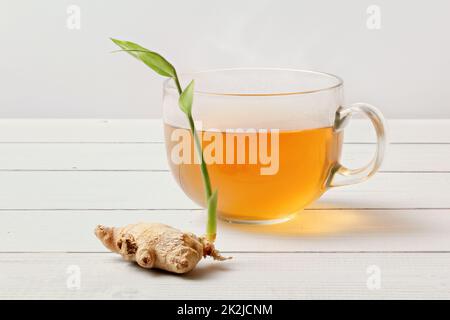 Vetro del preparato di fresco tè, secco di radice di zenzero con il germoglio verde accanto ad essa. Foto Stock