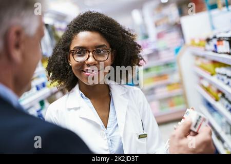 ILL prendere uno Grazie. Shot di una giovane farmacista utile aiutare un cliente con la scelta del farmaco giusto in farmacia. Foto Stock