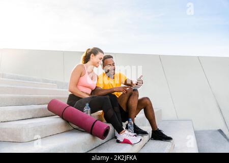 Allenamento sportivo interrazziale di coppia all'aperto - coppia multirazziale indossando abbigliamento sportivo e facendo allenamento funzionale all'aperto per tendere i muscoli del corpo, Foto Stock