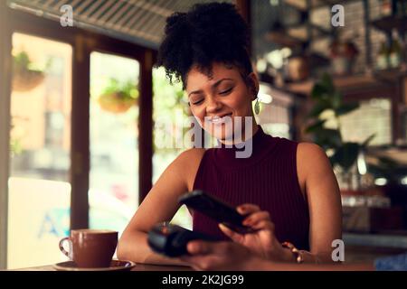 Amare quanto è facile pagare. Scatto corto di una giovane donna che paga utilizzando la tecnologia NFC in un bar. Foto Stock