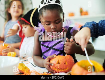 La zucca spezia e tutto bello. Shot di un gruppo di bambini che puliscono le zucche a una festa. Foto Stock