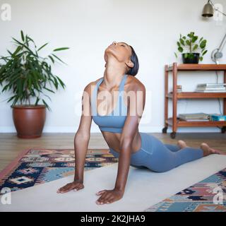 Una sessione di yoga è proprio ciò di cui avete bisogno. Scatto di una bella giovane donna che pratica yoga a casa. Foto Stock