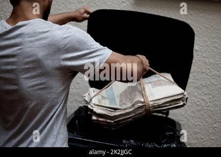 L'organizzazione è fondamentale. Colpo di un giovane uomo che mette il giornale nel bidone per essere riciclato. Foto Stock