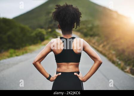 È il momento di tornare in pista. Dietro l'inquadratura di un giovane sportivo irriconoscibile in piedi con le mani sulle anche all'esterno. Foto Stock