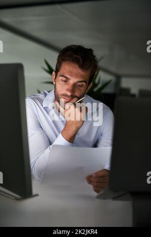 Mettendo nelle ore per realizzare il successo. Shot di un giovane uomo d'affari che lavora tardi in ufficio. Foto Stock