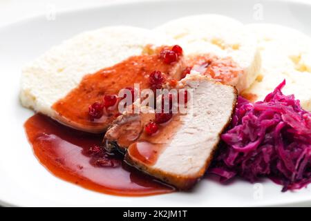 carne di maiale con cavolo rosso, salsa di mirtilli e gnocchi Foto Stock