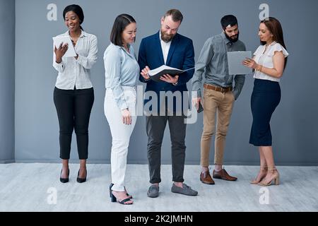 Costruire relazioni collaborative e una cultura del lavoro cooperativo. Colpo di un gruppo di uomini d'affari che lavorano su uno sfondo grigio. Foto Stock