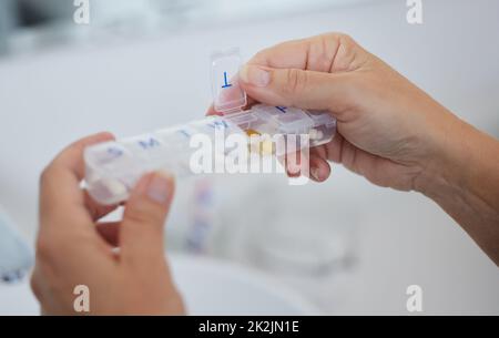 Questo mi aiuta a prendere tutti i miei meds in tempo. Scatto corto di una donna anziana che tiene la sua scatola settimanale della pillola. Foto Stock