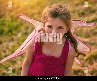 Bella come una foto in rosa. Ritratto di una bambina carina che guarda verso l'alto la macchina fotografica mentre gioca nel parco. Foto Stock