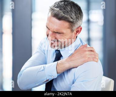 Il mal di schiena è un tale dolore. Shot di un uomo d'affari maturo che soffre di mal di schiena al lavoro. Foto Stock