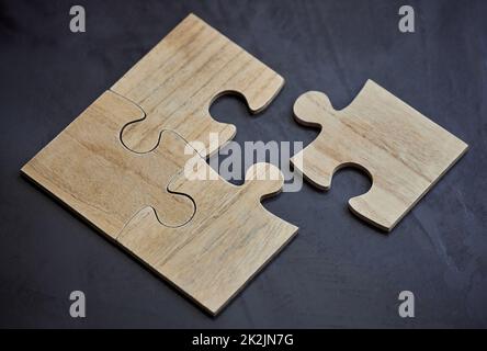 C'è sempre un pezzo che si adatta. Scatto di pezzi di puzzle che si trovano su una scrivania in un ufficio vuoto durante il giorno. Foto Stock