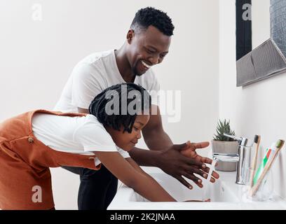 Tempo di lavare tutti quei germi fuori. Colpo di un giovane padre che aiuta sua figlia a lavarsi le mani nel bagno di casa. Foto Stock