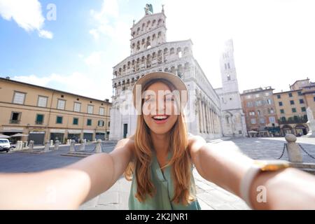 Sorridente ragazza viaggiatore scatta foto selfie nella storica città di Lucca, Toscana, Italia Foto Stock