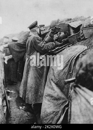 I Guerra Mondiale 1914-1918: una guerra di trincea - soldato tedesco in piedi in una trincea e cottura di una mitragliatrice, 1915. Militare, esercito, arma, automatico Foto Stock