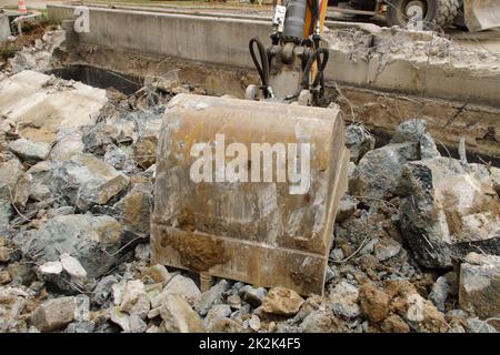 Caricamento di macerie da costruzione con un escavatore in un ambiente polveroso Foto Stock