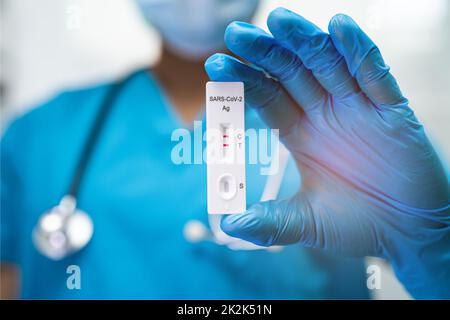 Il medico asiatico in tuta PPE mostra risultati positivi del test con saliva A. Foto Stock